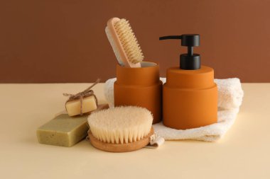 Kahverengi duvarın yanındaki masada banyo aksesuarları var.