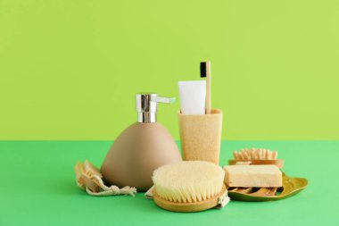Yeşil arka planda masaj fırçası olan banyo aksesuarları