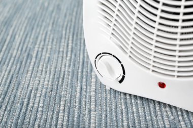 Mavi halıda elektrikli vantilatör ısıtıcısı, yakın plan.