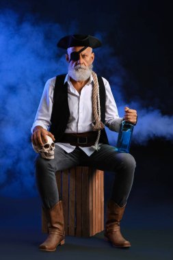 İnsan kafatasına sahip yaşlı bir korsan ve koyu arkaplanda bir şişe rom.