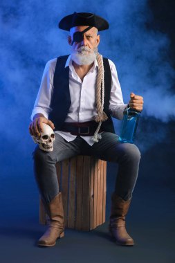 İnsan kafatasına sahip yaşlı bir korsan ve koyu arkaplanda bir şişe rom.