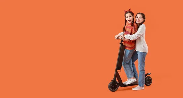 Porträtt Söta Tvillingflickor Med Sparkcykel Orange Bakgrund Med Utrymme För — Stockfoto