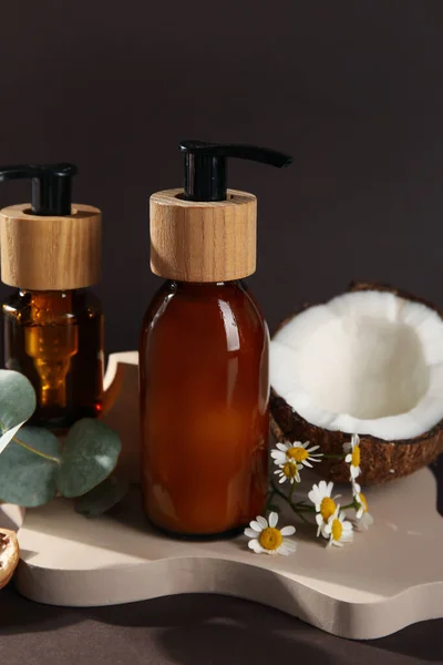 Composition with bottles of cosmetic products and natural ingredients on dark background, closeup