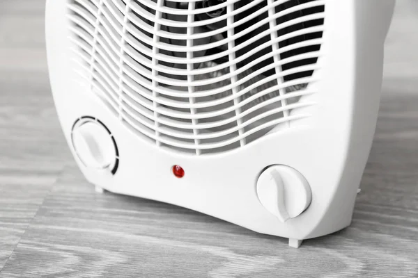 Electric fan heater on wooden floor, closeup