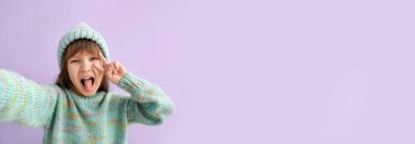 Kış giysileri içinde mutlu küçük kız eflatun arka planda mesaj için yer var.