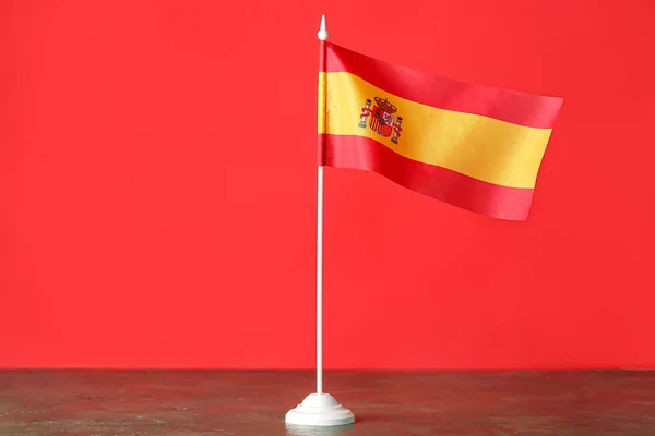 Flagge Spaniens Auf Dem Tisch Vor Rotem Hintergrund — Stockfoto