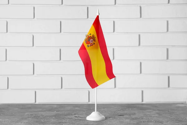 ライトレンガの壁の近くのテーブルの上にスペインの旗 — ストック写真