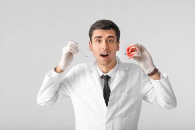 Plastik çene modeli ve ışık arkaplanda ayna olan erkek dişçi