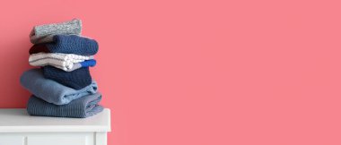 Odadaki pembe duvarın yanındaki masada sıcak örülmüş süveter yığını.