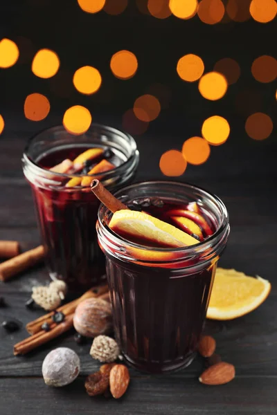 Glasses of delicious mulled wine on dark wooden table