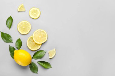 Gri arka planda taze limon ve yeşil yapraklı kompozisyon