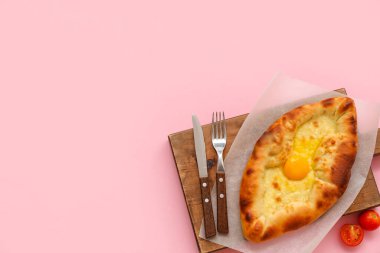 Pembe arka planda lezzetli Ajarian Khachapuri tahtasına sahip tahta tahta tahta.