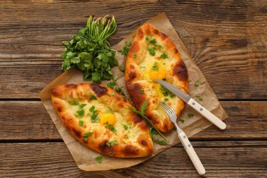 Ahşap arka planda kişniş olan lezzetli Ajarian khachapuri.