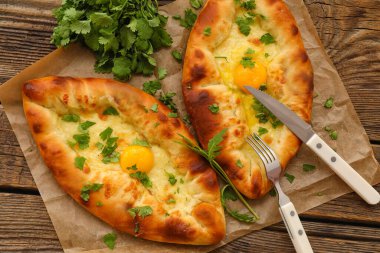 Ahşap arka planında kişniş olan lezzetli Ajarian Khachapuri, yakın plan.