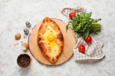 Lezzetli Ajarian Khachapuri, baharatlar, domatesler ve açık arkaplanda roka ile kompozisyon