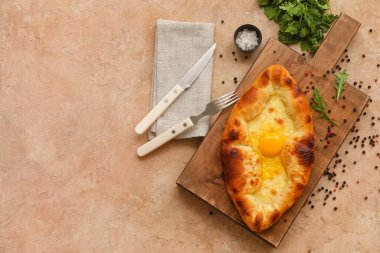 Lezzetli Ajarian Khachapuri tahtasıyla ahşap tahta ve renkli arka planda biber.