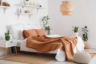 Ev bitkileri ve raflarla aydınlık yatak odasının içinde.