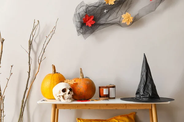 Table with Halloween decor near light wall