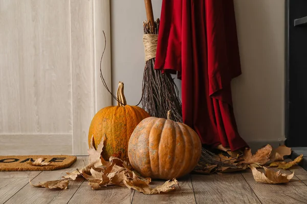 落ちた葉 ほうきと部屋のドアの近くの魔女のマントを持つハロウィーンのカボチャ — ストック写真
