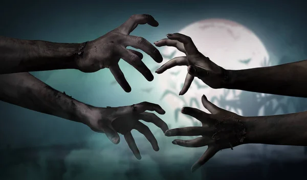 Hands of zombies and full moon in night sky