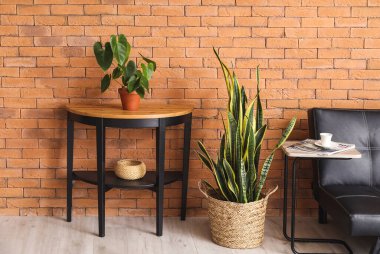 Oturma odasındaki tuğla duvarın yanındaki çiçekli masa.