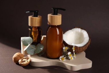 Composition with bottles of cosmetic products and natural ingredients on dark background