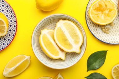 Sarı arka planda taze olgun limonlu tabaklar, yakın plan.