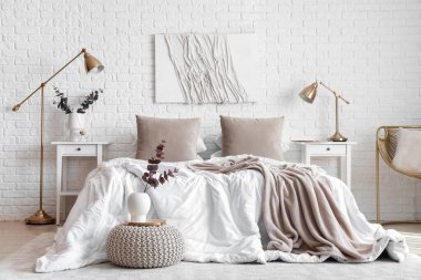 Masalar, lambalar ve vazolarda okaliptüs dallarıyla aydınlık yatak odasının içi.