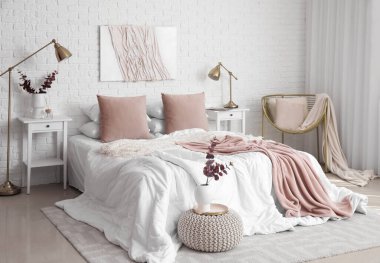 Masalar, lambalar ve vazolarda okaliptüs dallarıyla aydınlık yatak odasının içi.