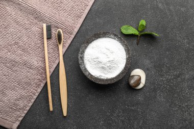 Diş fırçası, çakıl taşı, havlu ve yapraklı bir kase diş pudrası.