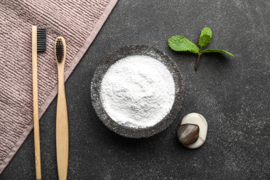 Diş fırçası, çakıl taşı, havlu ve yapraklı bir kase diş pudrası.