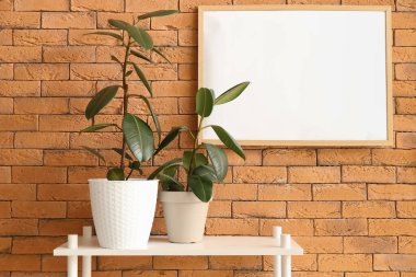 Yeşil çiçekli raf ve tuğla duvarda boş çerçeve