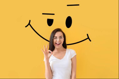 Havalı genç bir kadın ve sarı arka planda çizilmiş bir gülümseme