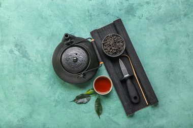 Bambu hasırı, bir kase kuru puer çayı, bıçak, bardak ve arkaplanda çaydanlık.