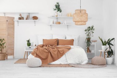 Ev bitkileri ve raflarla aydınlık yatak odasının içinde.