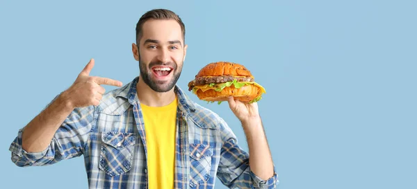 Young Man Holding Tasty Burger Light Blue Background Space Text — Stock Photo, Image