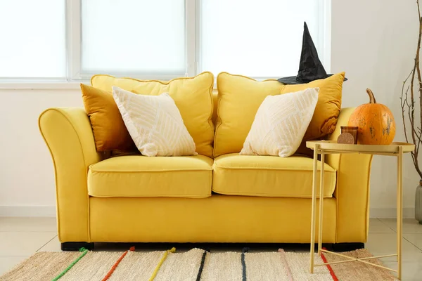 Yellow sofa with witch hat and table in room