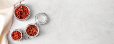 Açık arkaplanda kurumuş goji üzümlü kavanozlar ve metin için yer var.