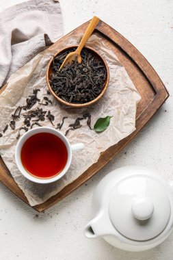 Kuru çay yapraklı kompozisyon ve beyaz arka planda bir fincan sıcak içecek.