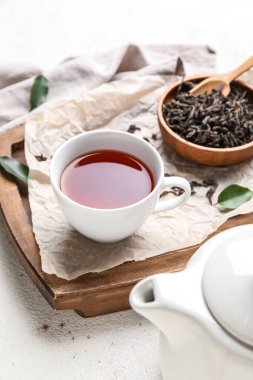 Kuru çay yapraklı kompozisyon ve beyaz arka planda bir fincan sıcak içecek.
