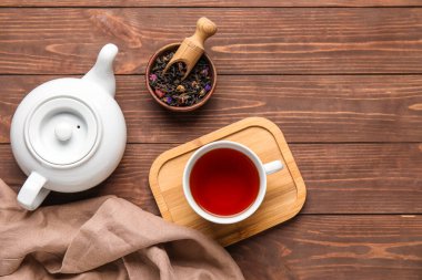 Kuru çay yapraklı kompozisyon ve ahşap zemin üzerinde sıcak içecek.
