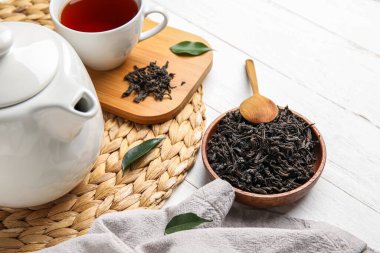 Kuru çay yapraklı kompozisyon ve beyaz ahşap arka planda sıcak içecek.