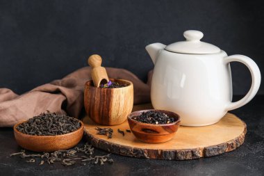 Kuru çay yapraklı kompozisyon ve koyu arkaplanda sıcak içecek.