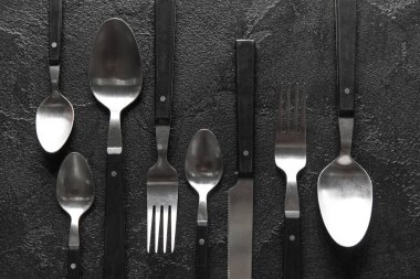 Koyu arkaplanda farklı çatal bıçak takımı, üst görünüm