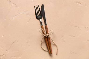 Bej arka planda kurdeleli çatal ve bıçak.