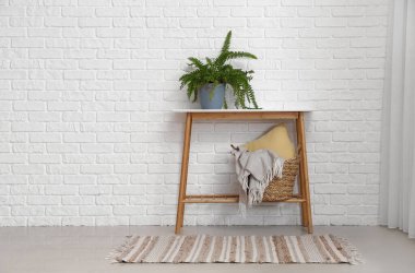 Yeşil çiçekli masa ve beyaz tuğla duvarın yanındaki sepet.