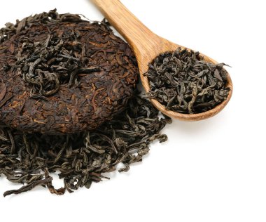 Beyaz arka planda bir kaşık kuru puer çayı.