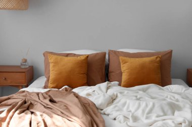 Gri duvarın yanında yumuşak yastıklı büyük bir yatak.