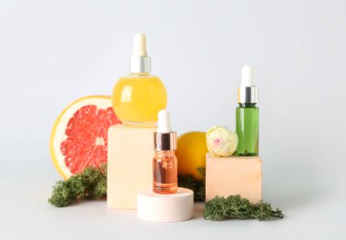 Gri zemin üzerinde turunçgil serumu şişeleri olan kompozisyon