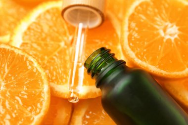 Portakal dilimlerine bir şişe C vitamini serumu, yakın plan.